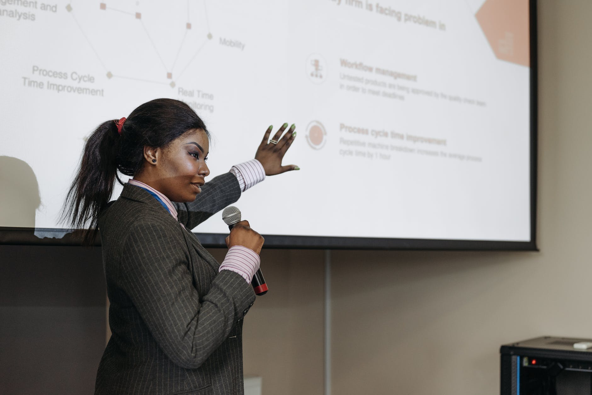 a woman holding a microphone while showing the projector screen